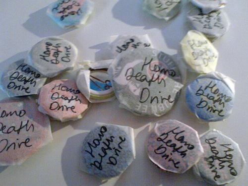 Badges with tape covering them and Homosexual Death Drive written in pen
